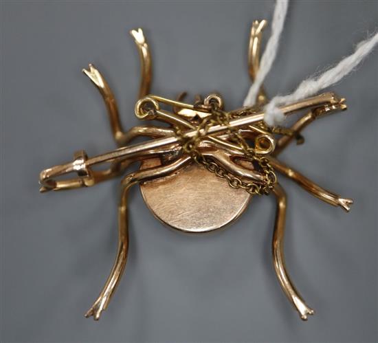 A yellow metal and chatoyant cabochon gem set spider brooch, 35mm, gross 10 grams.